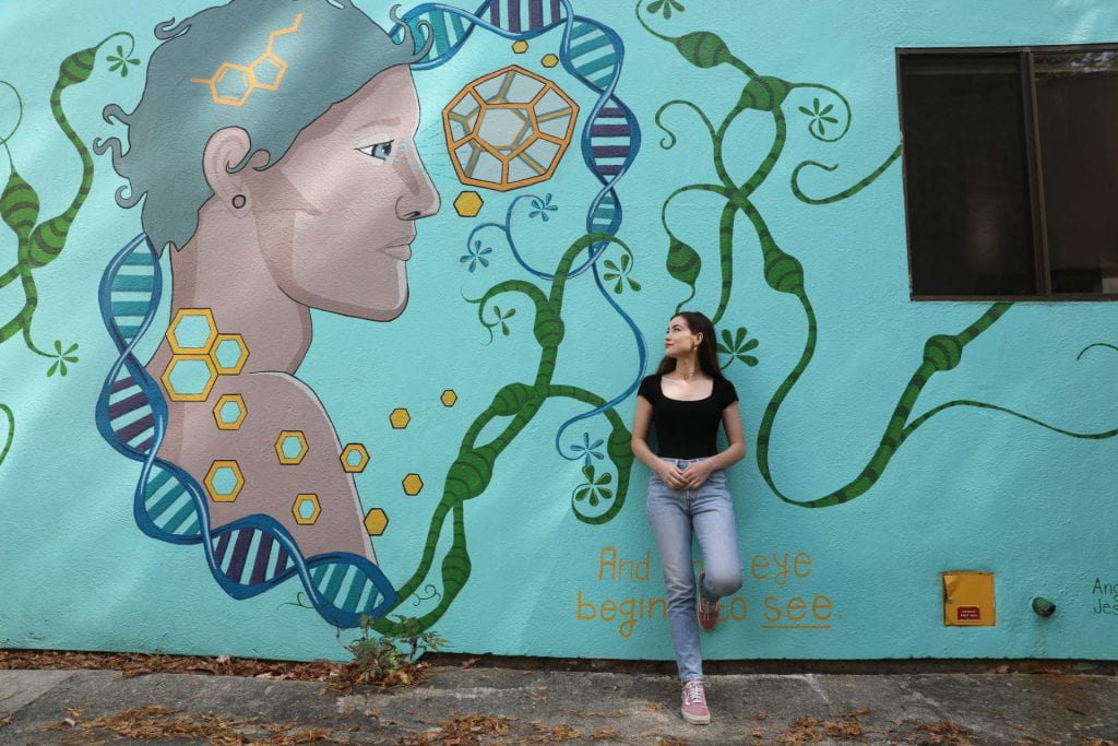 A girl standing in front of a mural at UCSC