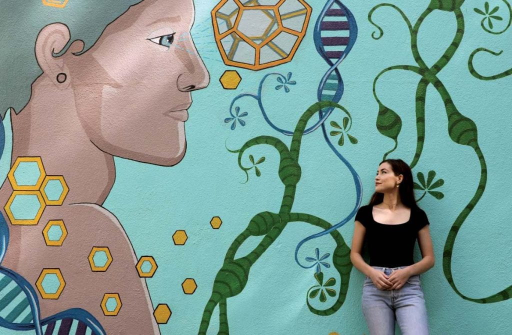 student in front of a mural