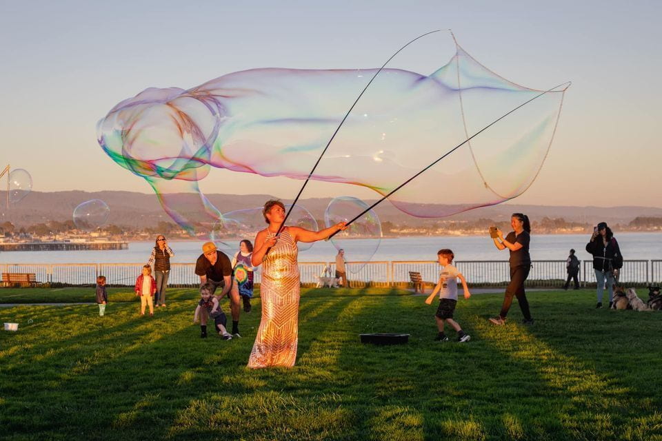 An outdoor art installation featuring an artist creating giant bubbles